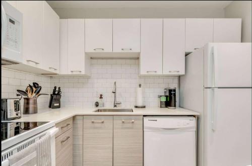 a kitchen with white cabinets and a white refrigerator at Casa Leslieville - 2BR Suite with LRG Patio in Toronto