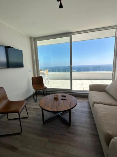 a living room with a couch and a coffee table at Depto privado con vista despejada al mar en 1 línea, terraza 20 mts y estacionamiento con acceso desde el borde costero in Vina del Mar