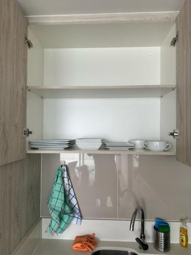 a kitchen with a sink and a shelf with utensils at Depto privado con vista despejada al mar en 1 línea, terraza 20 mts y estacionamiento con acceso desde el borde costero in Vina del Mar