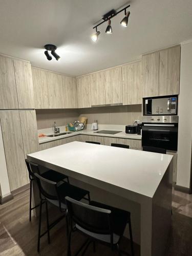 a kitchen with a white table and chairs in it at Depto privado con vista despejada al mar en 1 línea, terraza 20 mts y estacionamiento con acceso desde el borde costero in Vina del Mar