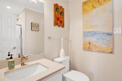 a bathroom with a sink and a toilet and a painting at TB Beach House in Dauphin Island