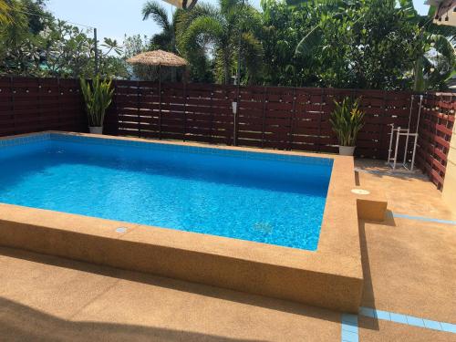 a swimming pool in a backyard with a fence at Suksabai Raiwan and Pool Villa in Jomtien Beach