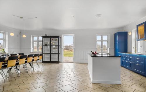 RøddingにあるBeautiful Home In Rødding With Wifiの青いキャビネットとテーブルと椅子のあるキッチン