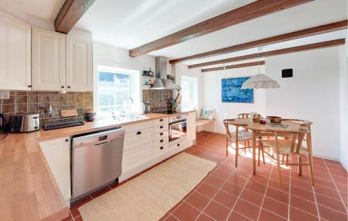 a kitchen with a table and a kitchen with white cabinets at Amazing Home In Munka-Ljungby With Wifi in Munka-Ljungby
