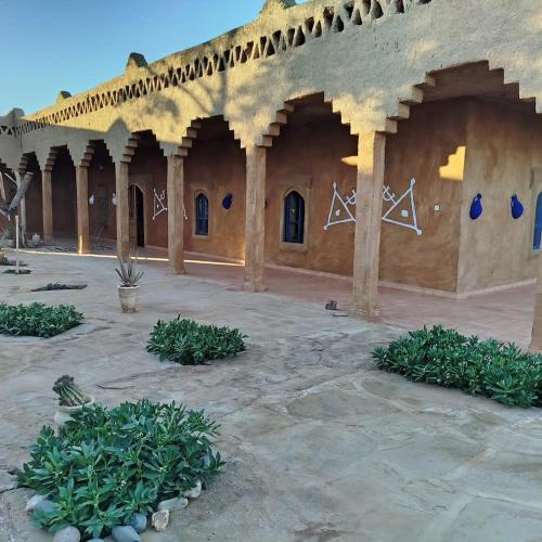 a courtyard of a building with arches and plants at Auberge Itrane in Merzane
