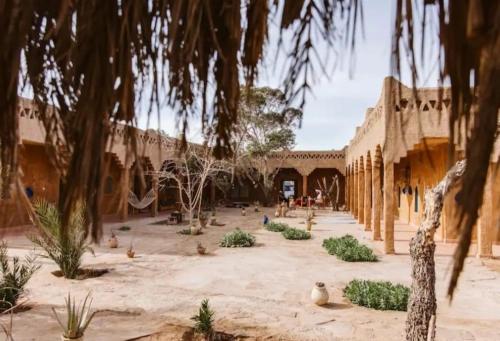 a courtyard of a building with trees and people in it at Auberge Itrane in Merzane
