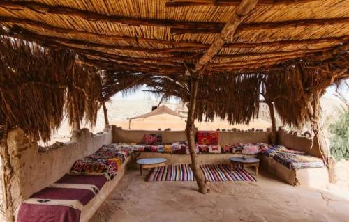 a group of couches sitting under a straw umbrella at Auberge Itrane in Merzane