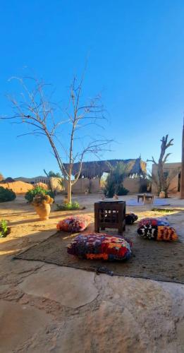 a bunch of pillows on the ground with a bench at Auberge Itrane in Merzane