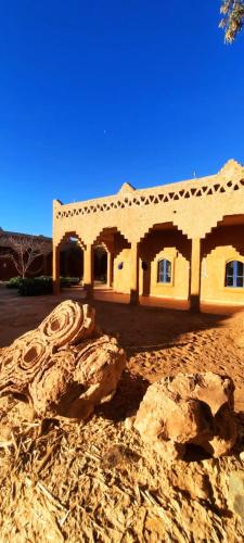 a house in the desert with a rock in front of it at Auberge Itrane in Merzane