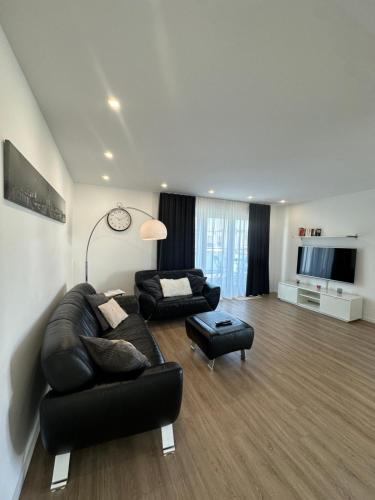 カールストにあるModernes deluxe Apartment für 4 Pers in Kaarst Nähe Düsseldorfのリビングルーム(黒い革張りのソファ、椅子付)