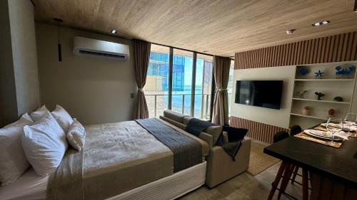a bedroom with a bed and a couch and a television at Apto Beira-Mar com Vista Mar - NT1206 in Maceió