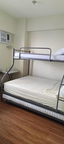 two bunk beds in a room with a wooden floor at DMCI TheOrabella QC,1 BR w/bal in Cubao38sqm condo in Manila