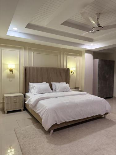a bedroom with a large white bed with a ceiling at Casa Bianca- Flat in Islamabad in Islamabad