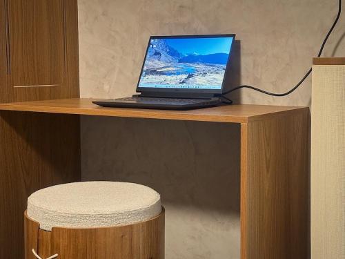 um computador portátil sentado numa secretária de madeira com um banco em Guarapari Apart1315 em Guarapari