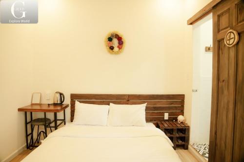 a bedroom with a bed with a wooden headboard and a table at Hoang Yen Villa & Coffee in Da Lat