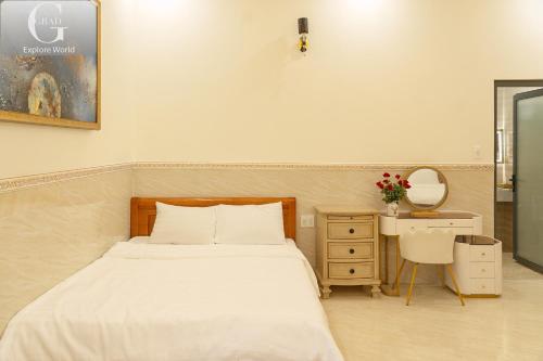 a bedroom with a bed and a desk and a mirror at Hoang Yen Villa & Coffee in Da Lat