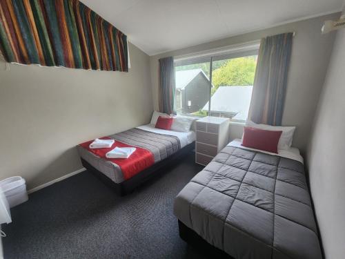 a hotel room with two beds and a window at Pinewood Queenstown in Queenstown