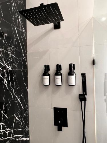 a bathroom with three bottles of soap on a wall at The Irish Inn Boutique Hotel in Shamrock
