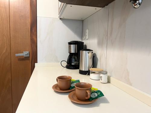 a kitchen counter with two cups and a coffee maker at Lujoso y soleado departamento en Sopocachi in La Paz