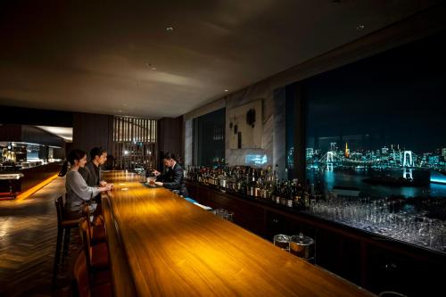 two people sitting at a bar with a view of a city at Grand Nikko Tokyo Daiba in Tokyo