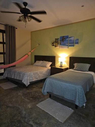 a bedroom with two beds and a ceiling fan at Casa Flamingos Altabi in Mérida