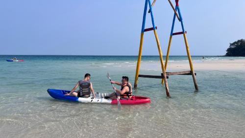 two men are sitting on a kayak in the ocean at Sunshine Resort Hotel Coconut Beach Koh Rong in Phumĭ Kaôh Rŏng