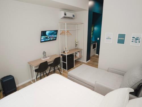 a room with a bed and a desk and a couch at Apê Santos Praia do Gonzaga in Santos