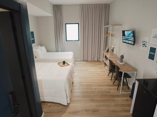a hotel room with two beds and a desk at Apê Santos Praia do Gonzaga in Santos
