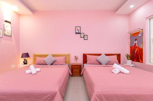 two beds in a room with pink walls at Căn Hộ "2" OaSky View biển 3 Phòng 5 Giường- Oasky Sea View Apartment in Vung Tau