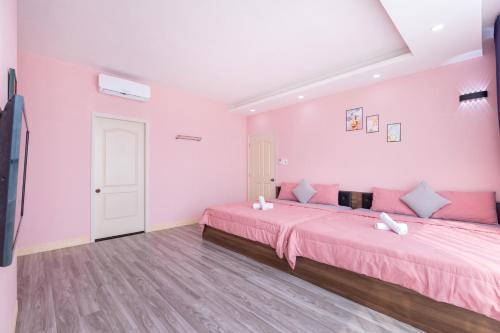 a pink bedroom with two beds and a tv at Căn Hộ "2" OaSky View biển 3 Phòng 5 Giường- Oasky Sea View Apartment in Vung Tau