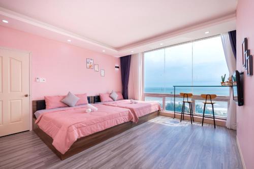a pink bedroom with a bed and a large window at Căn Hộ "2" OaSky View biển 3 Phòng 5 Giường- Oasky Sea View Apartment in Vung Tau