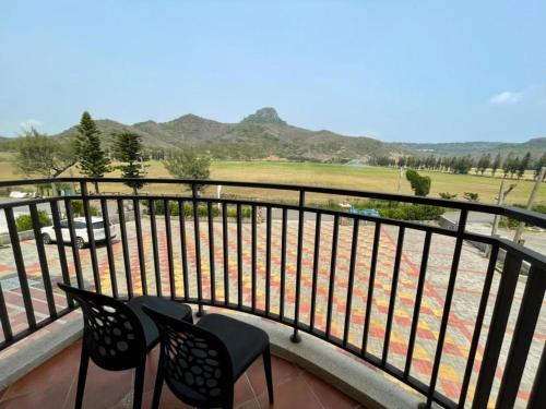 a balcony with two chairs and a view of a golf course at Island on the Sea in Kenting
