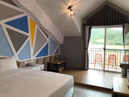 a bedroom with a bed and a balcony with chairs at Island on the Sea in Kenting