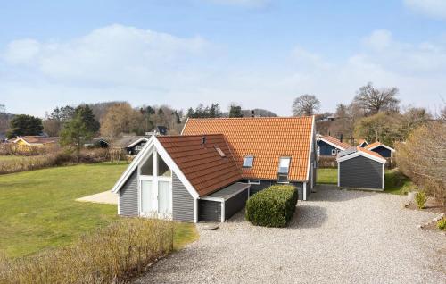 a small house with an orange roof in a yard at Awesome Home In Rudkøbing With Sauna in Spodsbjerg