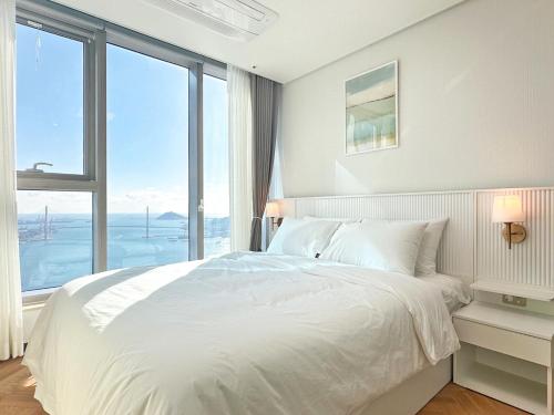 a bedroom with a white bed with a large window at Brown Suites Busan Station in Busan