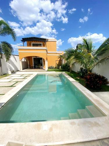 a villa with a swimming pool in front of a house at Casa Flamingos Altabi in Mérida