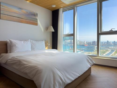 a bedroom with a large white bed with large windows at Brown Suites Busan Station in Busan