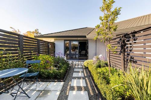 a garden with a fence and a table and chairs at Potager B&B- Waiohine- Greytown in Greytown