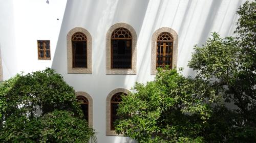 a white building with windows and trees in front at Riad Sabah in Fès