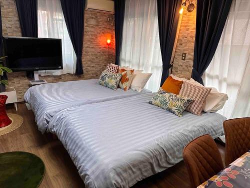 una camera da letto con due letti e una TV a schermo piatto di 2 Double bed and 1 Sofa bed Fullsize bathroom Shinjuku 20 minutes Quiet cozy room Walmart DonDonDonk Station 7 minutes Free parking at Tanashi Station a Nishitokyo