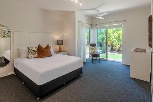 Un dormitorio con una cama blanca y una puerta corrediza de vidrio. en Cooinda Gardens 6 on Hamilton Island by HamoRent, en Hamilton Island