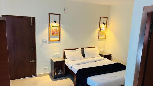 a bedroom with two beds and two lights on the wall at Hidden doors apartment in Ooty