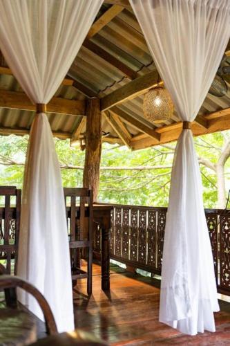 a porch with white curtains and a table and chairs at Monraumsuk home stay Chiang Mai in Ban Pok Nai