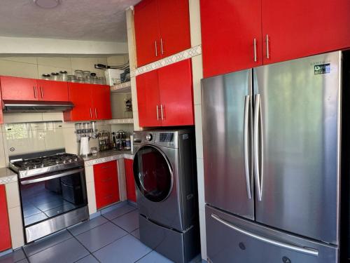 a kitchen with red cabinets and a stainless steel refrigerator at Casa Mismaloya Selva in Cedro