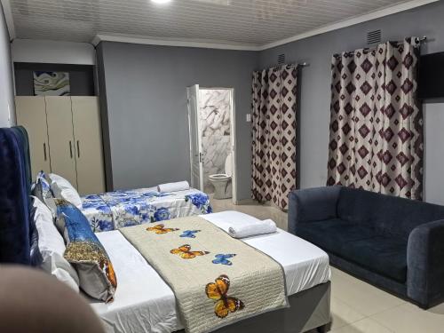 a bedroom with two beds and a blue couch at Gift Guest house 2 in Cravenby