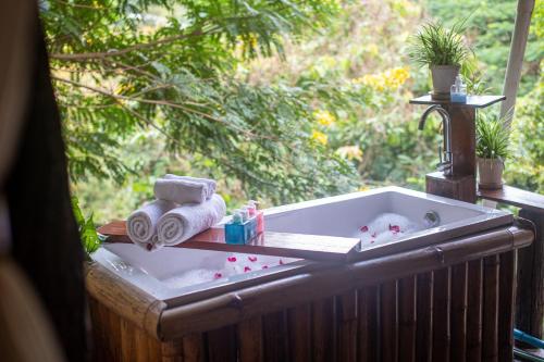 a bath tub with two towels and a towel rack at Monraumsuk home stay Chiang Mai in Ban Pok Nai