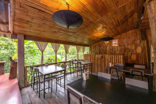 a restaurant with tables and chairs and a wooden ceiling at Monraumsuk home stay Chiang Mai in Ban Pok Nai