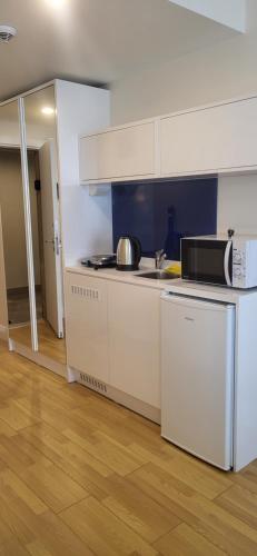 a kitchen with white cabinets and a sink and a microwave at Batumi Orbi D2, V&O seaview studio in Batumi