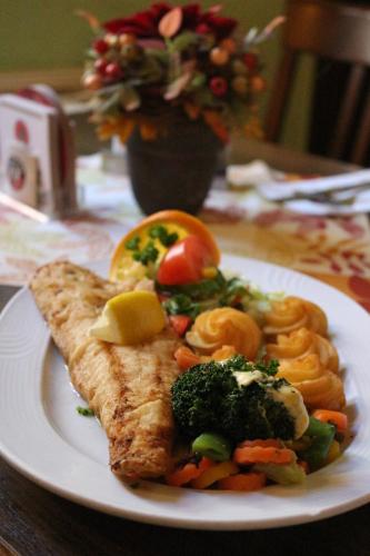 a plate of food with a piece of fish and vegetables at Gasthof Zur guten Quelle in Schwerin