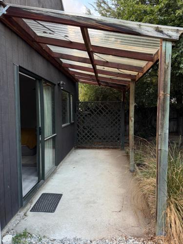 une pergola en bois sur le côté d'une maison dans l'établissement Sleepout on Stone St, à Wanaka